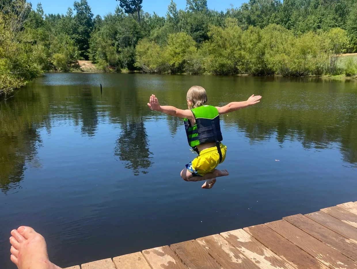 Boy jumping into campground pond