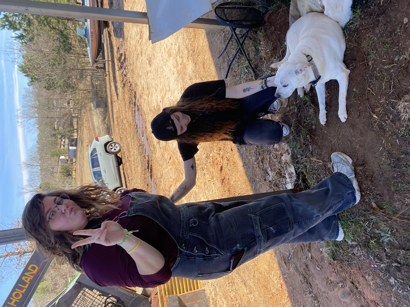 Two people posing for camera, one holding up a peace sign, the other petting a dog