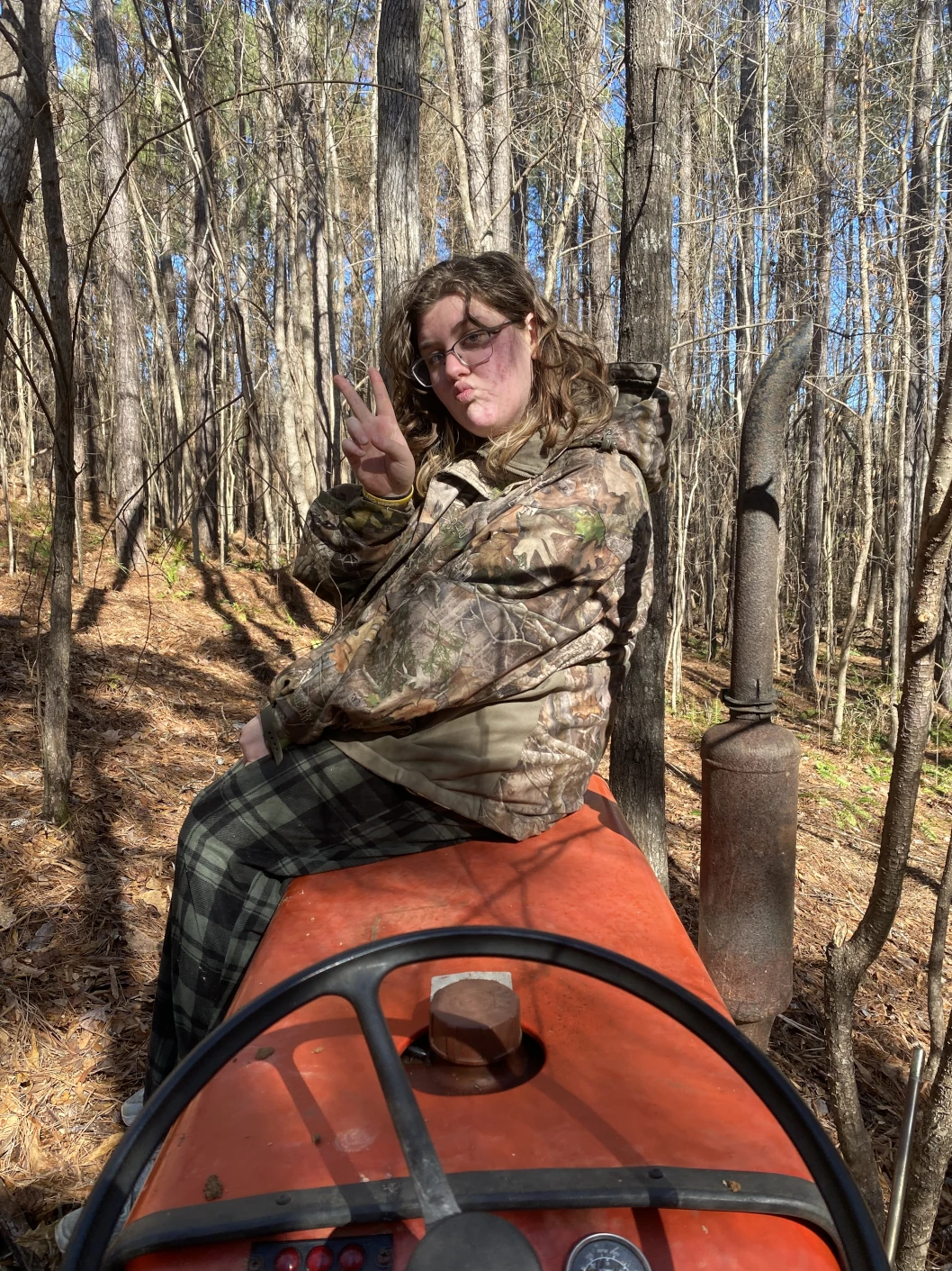 One person posing with a peace sign on the hood of a tractor.