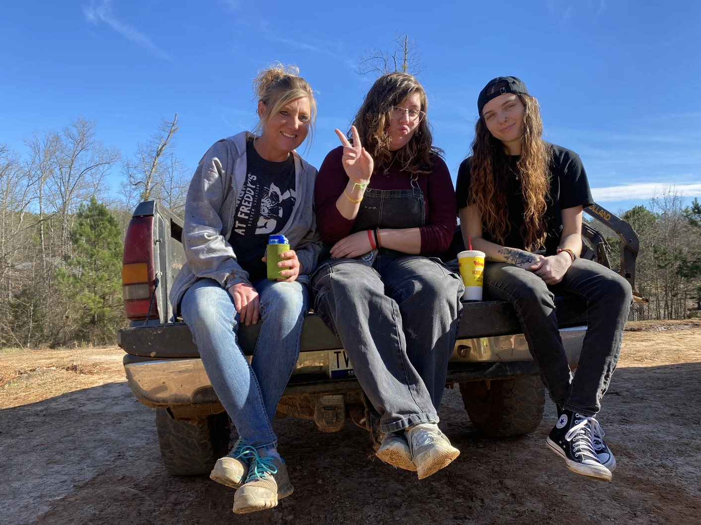 Three adult women posing on a truck tailgate