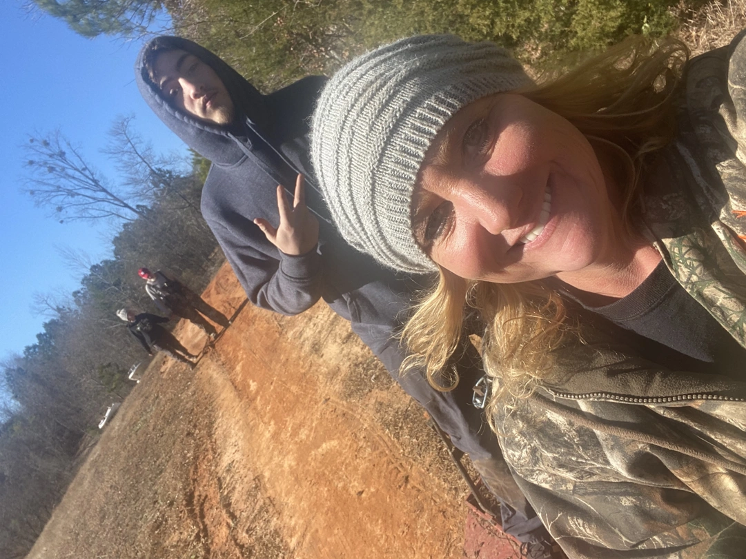 Two people posing for camera with two more in the background on a dirt road