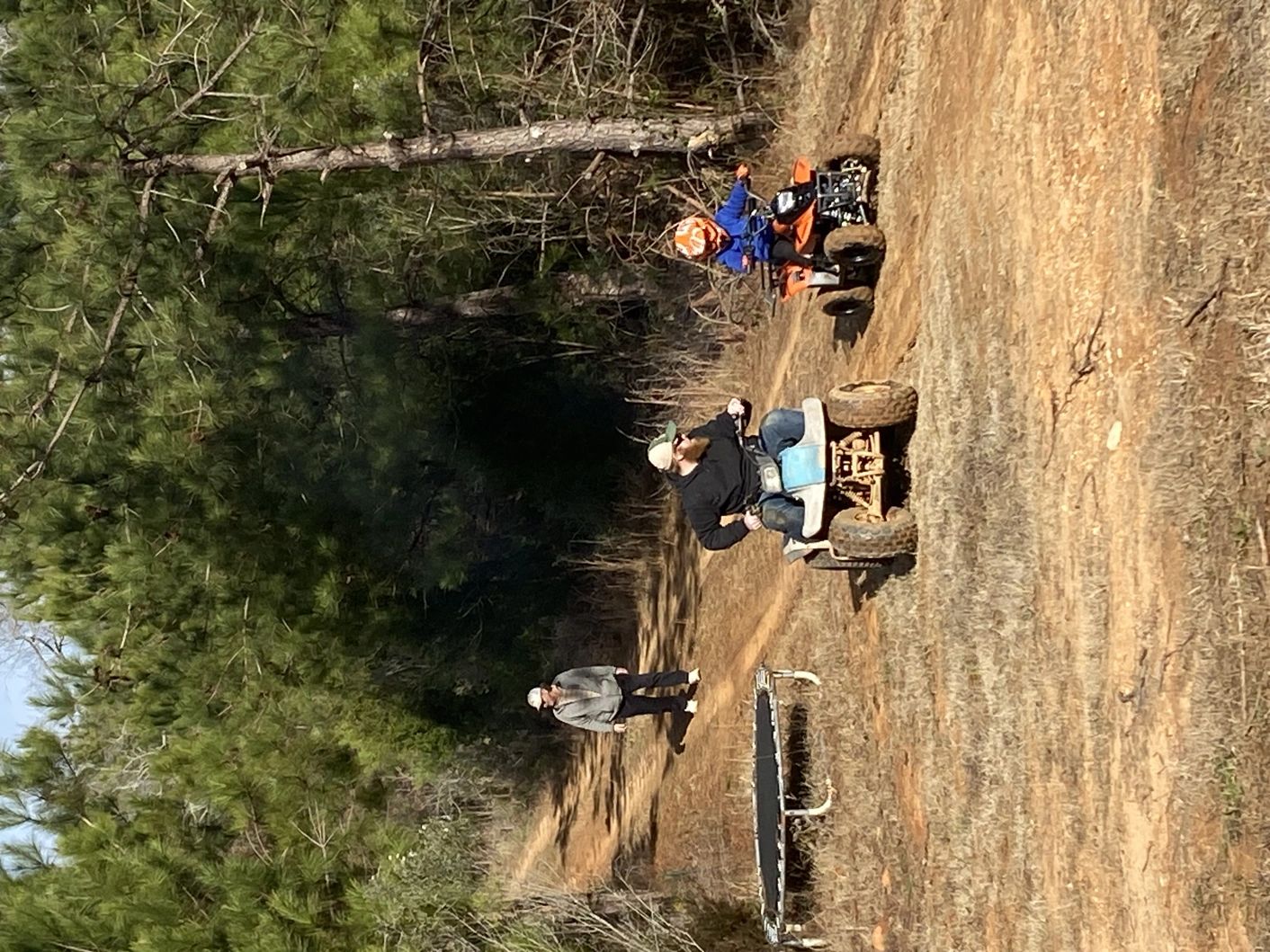 Three people on a trail, two riding ATVs