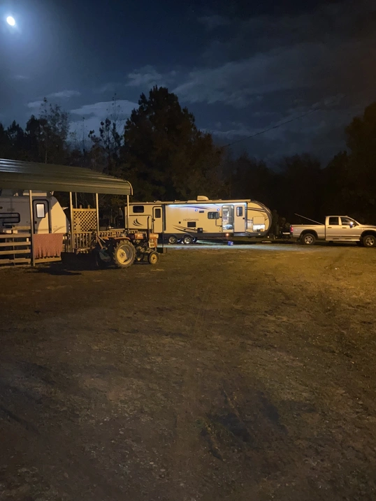 Camper attached to a truck with another camper under a car port beside it