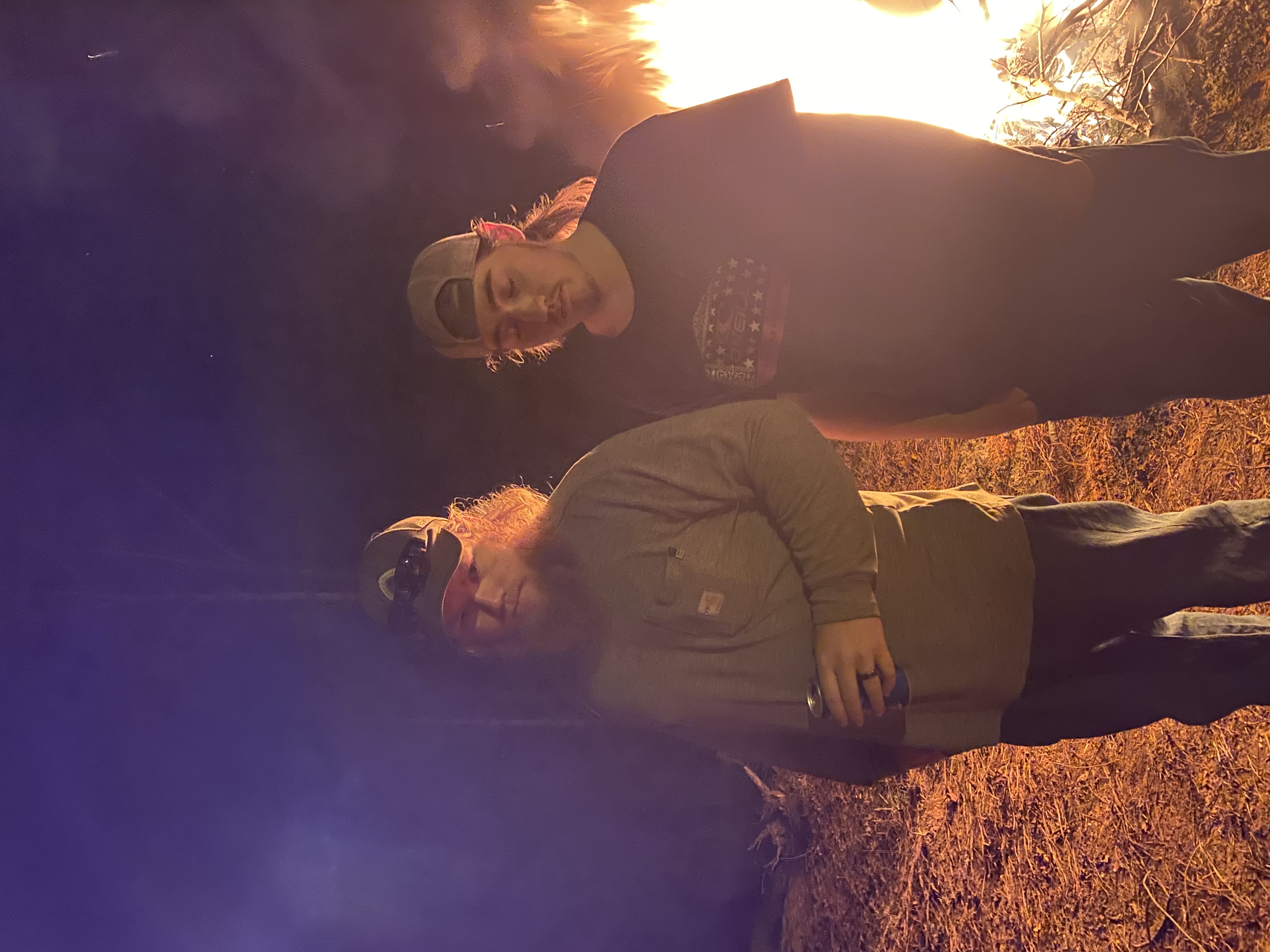 Two people posing in front of a bonfire