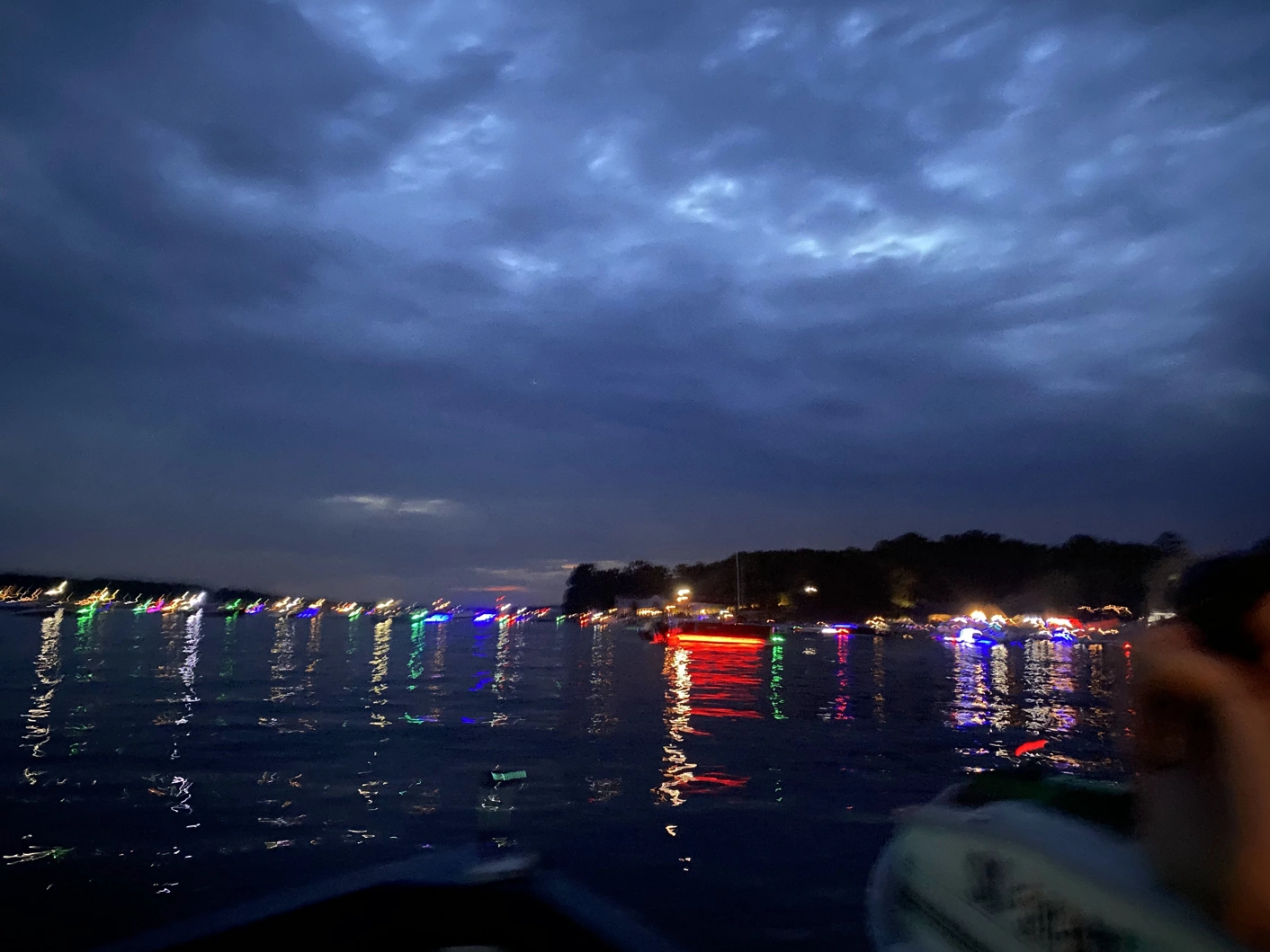 Lake at night lights of several boats and houses in the distance