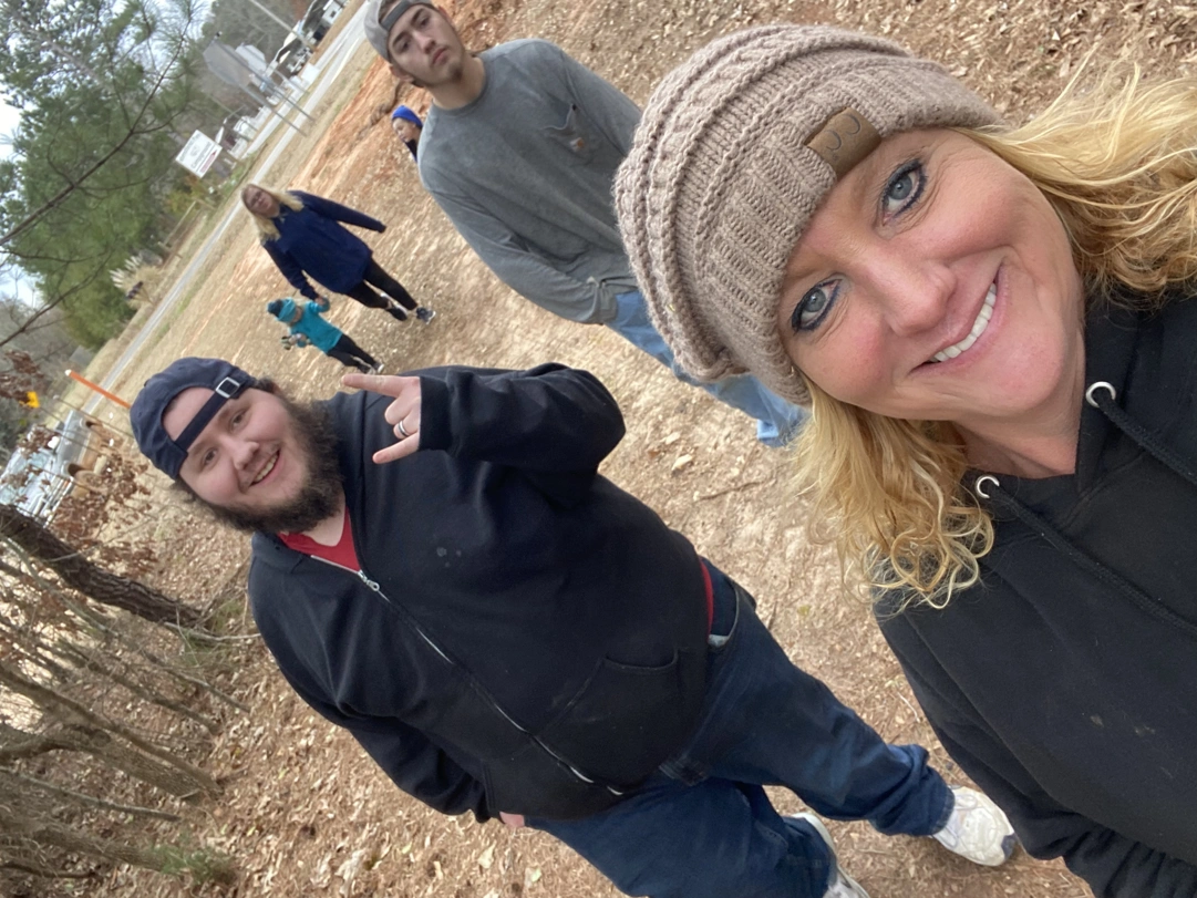 Six people walking a nature trail, two posing for camera, four in the background.